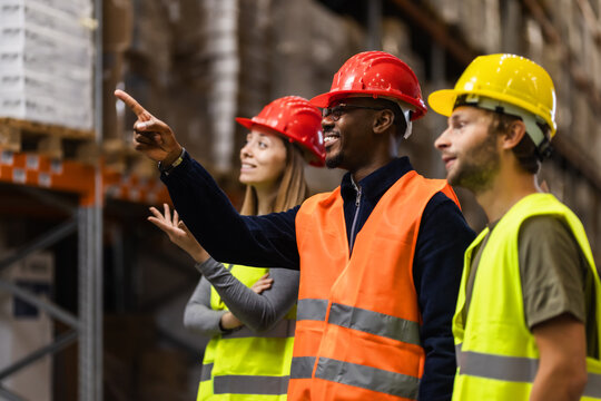 Diverse warehouse workers in safety gear discussing logistics and storage