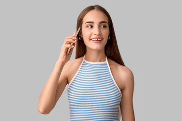 Young woman with diastema talking by mobile phone on light background