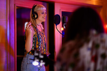 Side view of professional female singer singing at neon lit music studio.