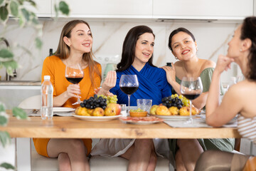 Girlfriends drinking wine and having conversation over dinner at a house party