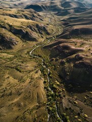 Aerial view of a winding desert river, surrounded by rugged mountains and sparse vegetation.