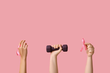 Female hands with dumbbell and pink ribbons on color background. Breast cancer awareness concept