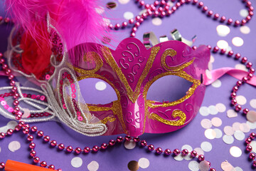 Beautiful pink carnival mask with decor on lilac background. Closeup