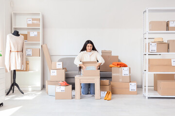 Fototapeta premium Young woman entrepreneur preparing online store orders for shipping in home office warehouse, she is carefully packaging products into cardboard boxes, surrounded by shelves filled with inventory