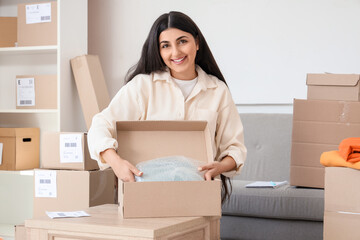 Female seller packing bag into parcel box in online store warehouse