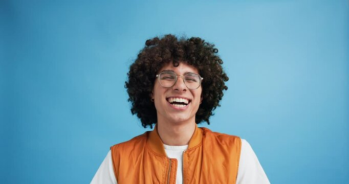 Laughing, student and face of man in studio for gen z meme, crazy youth and happiness. Funny, comedy and silly with male person and joke on blue background for comic, hilarious and humor emoji
