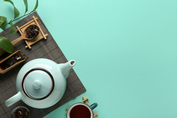 Beautiful composition with stylish tea pot and bamboo mat on turquoise background