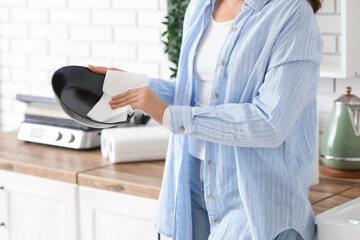 Beautiful young woman wiping bowl with paper towels in kitchen, closeup
