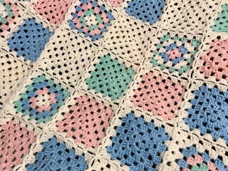 Granny square crocheted blanket with different colors motives, retro vintage craft handmade handiwork crocheting, beautiful plied photo cozy winter or autumn background wool thing yarn lovely warm