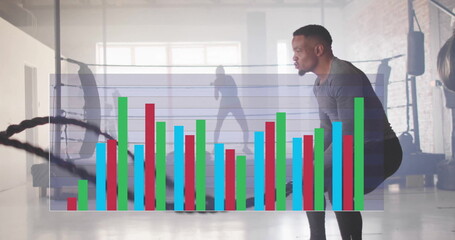 Image of data processing and diagrams over biracial man exercising with ropes at gym
