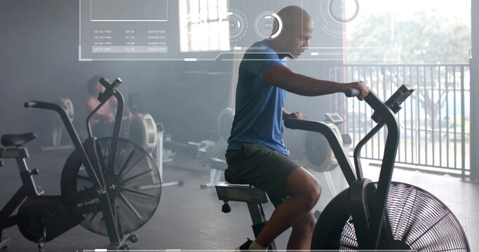 Image of data processing and diagrams over biracial man exercising with elliptical bikes at gym