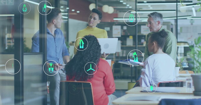 Image of ecology icons over diverse colleagues discussing work in office