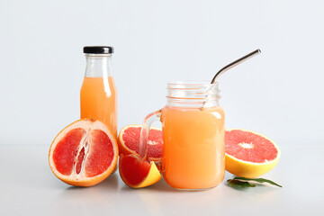 Fresh grapefruits, bottle and mason jar with  juice on grey background