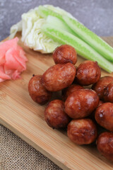 Thai northeastern sausage (Sai Krok Isan) made from fermented pork and rice eat with cabbage, cucumber and pink ginger. Street food market