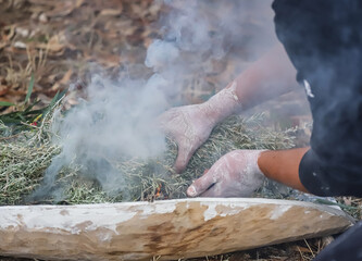 Human hands with green branches, wooden ritual dish and fire, Australian aboriginal smoking...