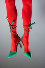 Sexy Christmas legs. Female legs wearing red tstockings and green high heels. Santa woman legs