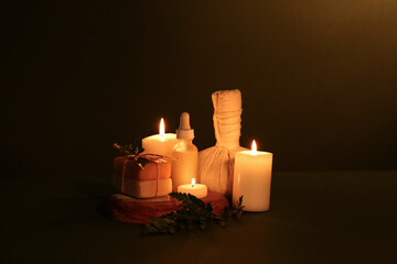 Spa composition with burning candles, massage bag and soap bars on dark color background