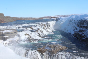 A majestic Icelandic waterfall surrounded by rugged terrain.