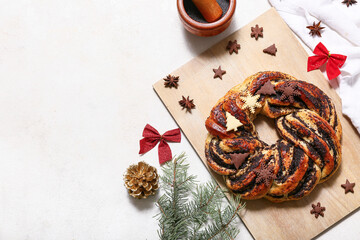 Wooden board with tasty Christmas pastry wreath, fir tree branches, decor and cookies on white background