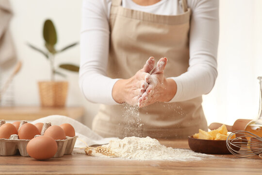 Woman preparing dough with ingredients on kitchen counter