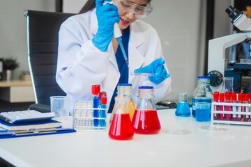 A young Asian woman works in a laboratory, conducting chemical and blood tests. Wearing goggles, research and analysis, combining science and technology in a professional and medical environment.