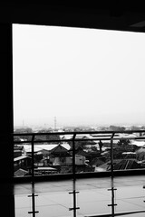 Balcony inside a tall building with silver railing with urban views in Indonesia with black and white mode