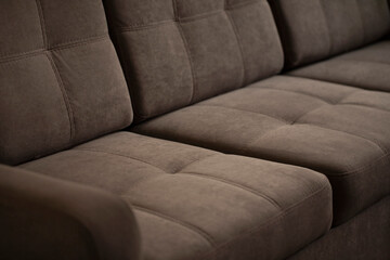A soft sofa made of brown velour with quilted stitched pillows with a comfortable back and seat....