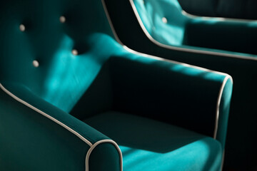 A set of soft turquoise velour armchairs with white piping and white button ties in the shadows and rays of the sun. Part of the armchair with a soft back and carriage tie close-up with copy space.