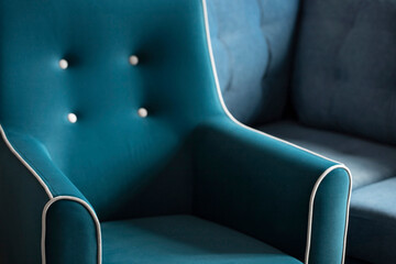 Soft turquoise velour armchair with white piping and white button ties in the shadows and rays of the sun. Part of the armchair with a soft back and carriage tie close-up with copy space.