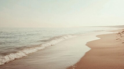 Fototapeta premium Serene beach scene with gentle waves and soft sand under a hazy sky.