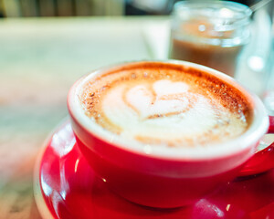 Romantic Latte Art in Red Cup with Heart Design on Frothy Coffee at Cozy Cafe Setting