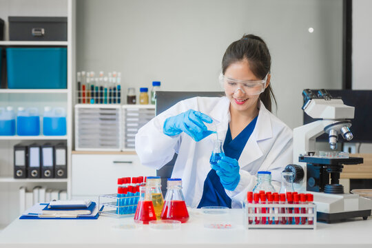 A young Asian woman works in a laboratory, conducting chemical and blood tests. Wearing goggles, research and analysis, combining science and technology in a professional and medical environment.