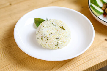 Lime leaf rice on wooden table. Fried onion on top. thisi is Indonesian cuisine on rattan plate. Nasi daun jeruk