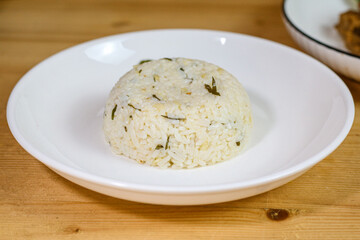 Lime leaf rice on wooden table. Fried onion on top. thisi is Indonesian cuisine on rattan plate. Nasi daun jeruk