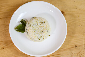 Lime leaf rice on wooden table. Fried onion on top. thisi is Indonesian cuisine on rattan plate. Nasi daun jeruk