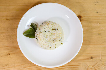 Lime leaf rice on wooden table. Fried onion on top. thisi is Indonesian cuisine on rattan plate. Nasi daun jeruk