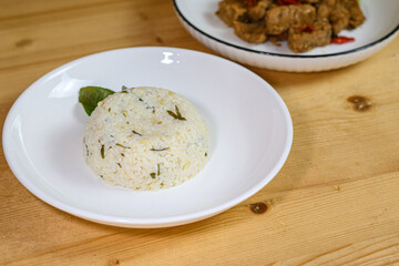 Lime leaf rice on wooden table. Fried onion on top. thisi is Indonesian cuisine on rattan plate. Nasi daun jeruk