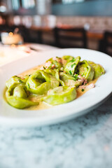 Delicious Green Tortellini Served on a White Plate in an Italian Restaurant Setting With Creamy Sauce and Fresh Herbs, Capturing the Essense of Italian Cuisine for Culinary Enthusiasts