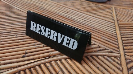 Reserved Sign, black acrylic at bamboo table white text