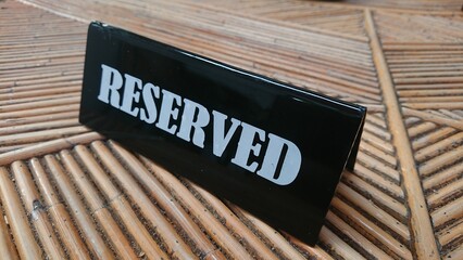 Reserved Sign, black acrylic at bamboo table white text