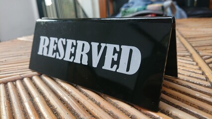 Reserved Sign, black acrylic at bamboo table white text