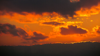 Dramatic sunset clouds painted in fiery orange hues marking the end of the day.