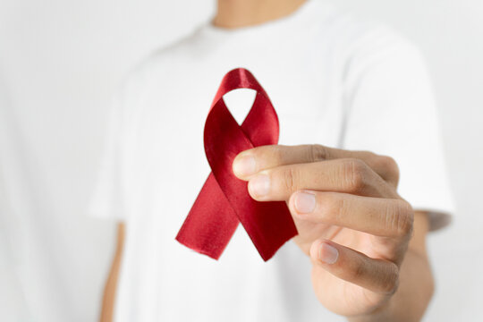 Hand holding Red Ribbon as a symbol for December World Aids Day (acquired immune deficiency syndrome). Aids day concept