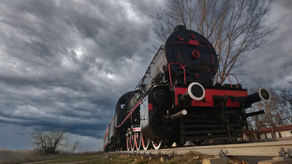 A vintage steam train under dramatic stormy skies, evoking nostalgia and power.