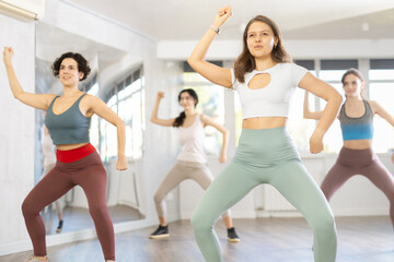 Fototapeta premium Young female coach conducts classes in modern energetic hip hop dancing for female company group. Concept of active hobby, pleasant way to lose weight and maintain perfect figure