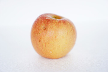 Fuji apple with uneven pink mixed yellow color with some water droplets on the skin isolated on white background