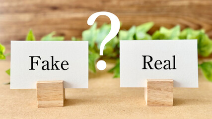 FakeとRealのカードとクエスチョンマークとツタ_茶色板背景