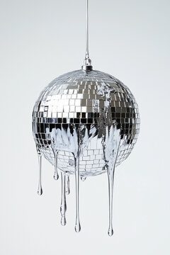 A disco ball dripping with silver liquid, on a white background