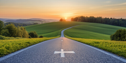 Winding asphalt road leading through rolling green hills towards the setting sun, symbolizing journey, travel, and new beginnings.