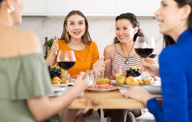 Girlfriends drinking wine and having conversation over dinner at a house party